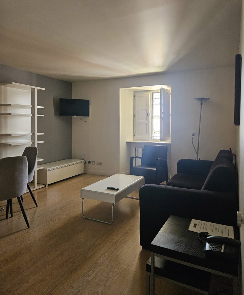 Vista de la sala, al fondo una ventana. Incluye dos sofás, dos mesitas auxiliares, butacas y mueble